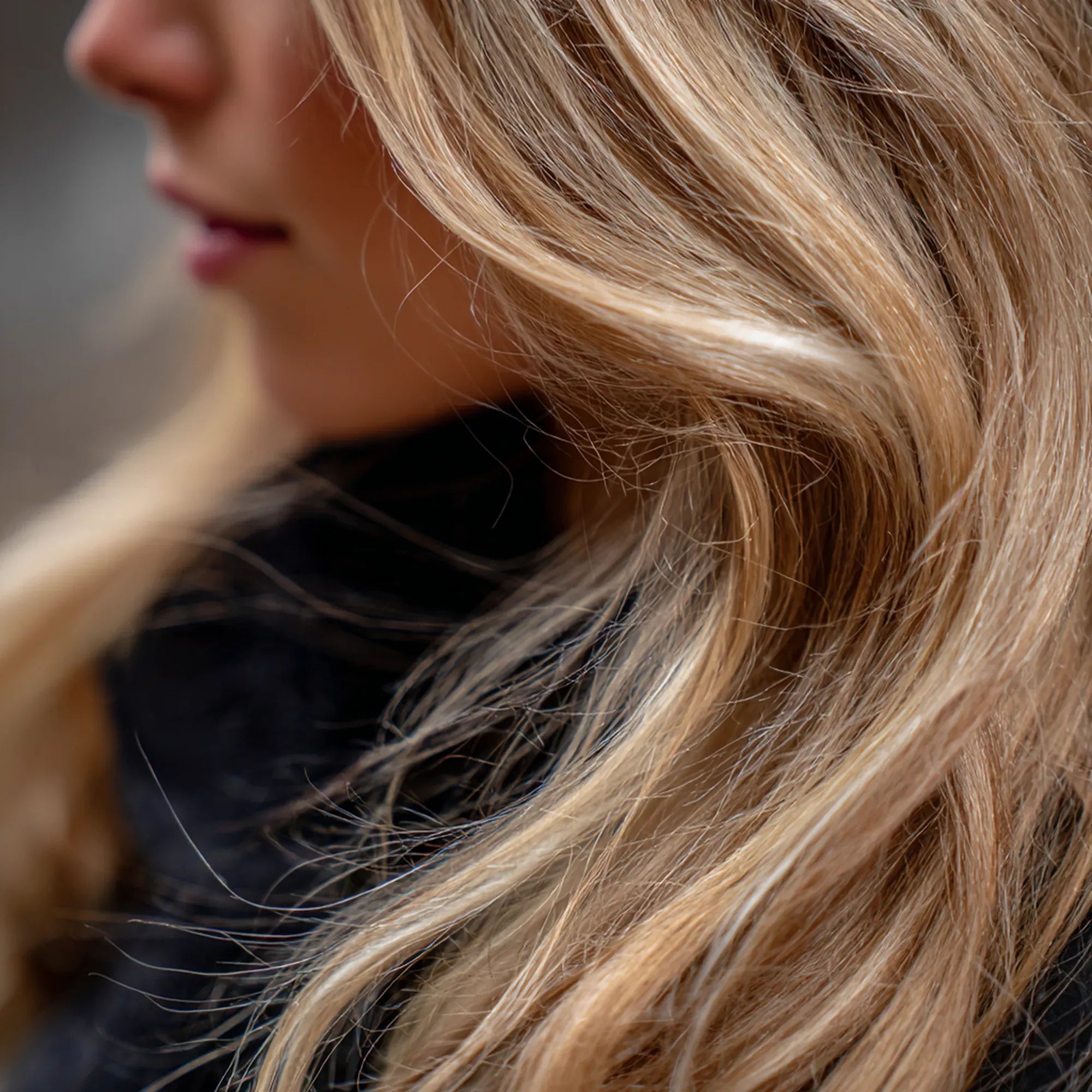 Woman with long, layered brown hair with blonde highlights and a shiny finish.